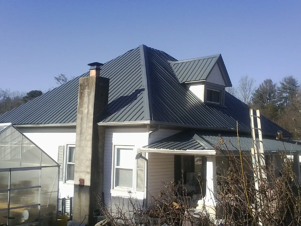 Dark blue standing seam metal roof on a white farmhouse with dormer — Slate & Tile Roof Repair by Roofing Brothers in Green Camp