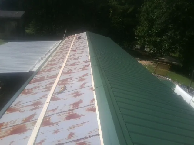 Old rusted panels beside newly installed green metal roofing — Wind Damage Roof Repair by Roofing Brothers in Green Camp
