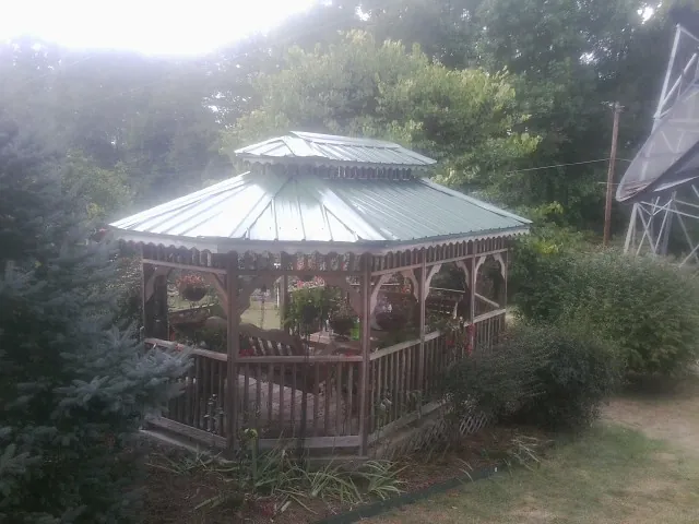 Green metal roof on a backyard gazebo surrounded by garden beds in Green Camp
