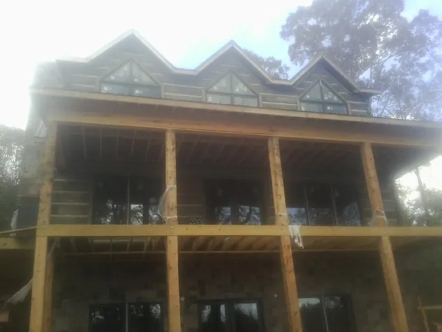 Dormers and porch framing on a large log home under construction — Roof Coating work by our crew in Green Camp