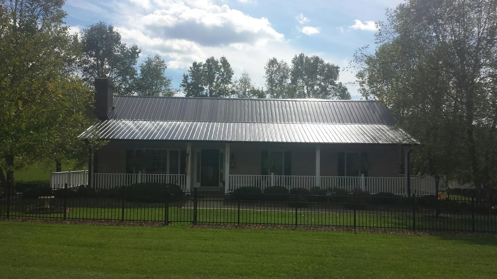 Gray metal roof on a brick ranch with a full width front porch — Gutter Guard Installation work by our crew in Green Camp