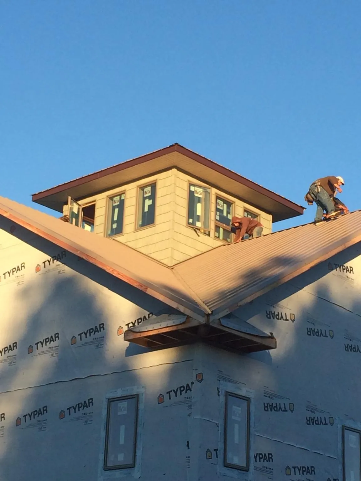 Roofers working around a rooftop cupola on a new metal roof at sunset — Roof Waterproofing in Green Camp by Roofing Brothers